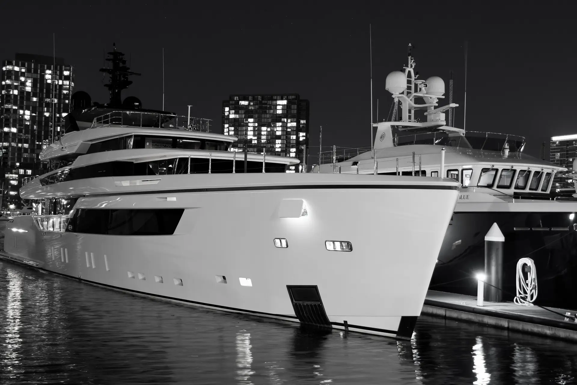 Luksuriøs yacht ved marina i nattlig havneby med dempet belysning